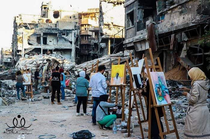 طلاب الفنون الجميلة يرسمون لوحاتهم على أنقاض الدمار والخراب في مخيم اليرموك